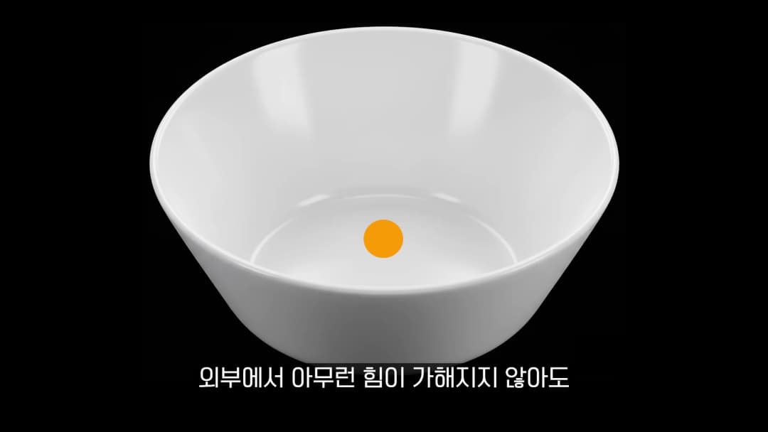 검은 배경 위에 놓인 흰색 그릇 안에 주황색 공이 하나 담겨 있는 모습
