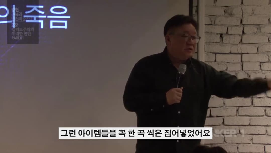 안경을 쓴 남성이 마이크를 들고 강연하는 모습