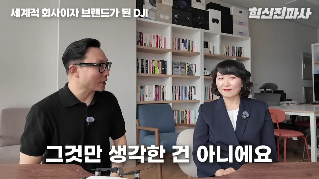 책장이 있는 사무실에서 남녀 두 사람이 대화를 나누고 있는 모습