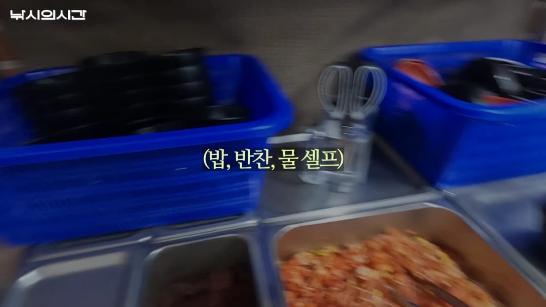 식당 내부에 밥과 반찬이 담긴 스테인리스 용기와 파란색 바구니들이 놓여 있는 모습